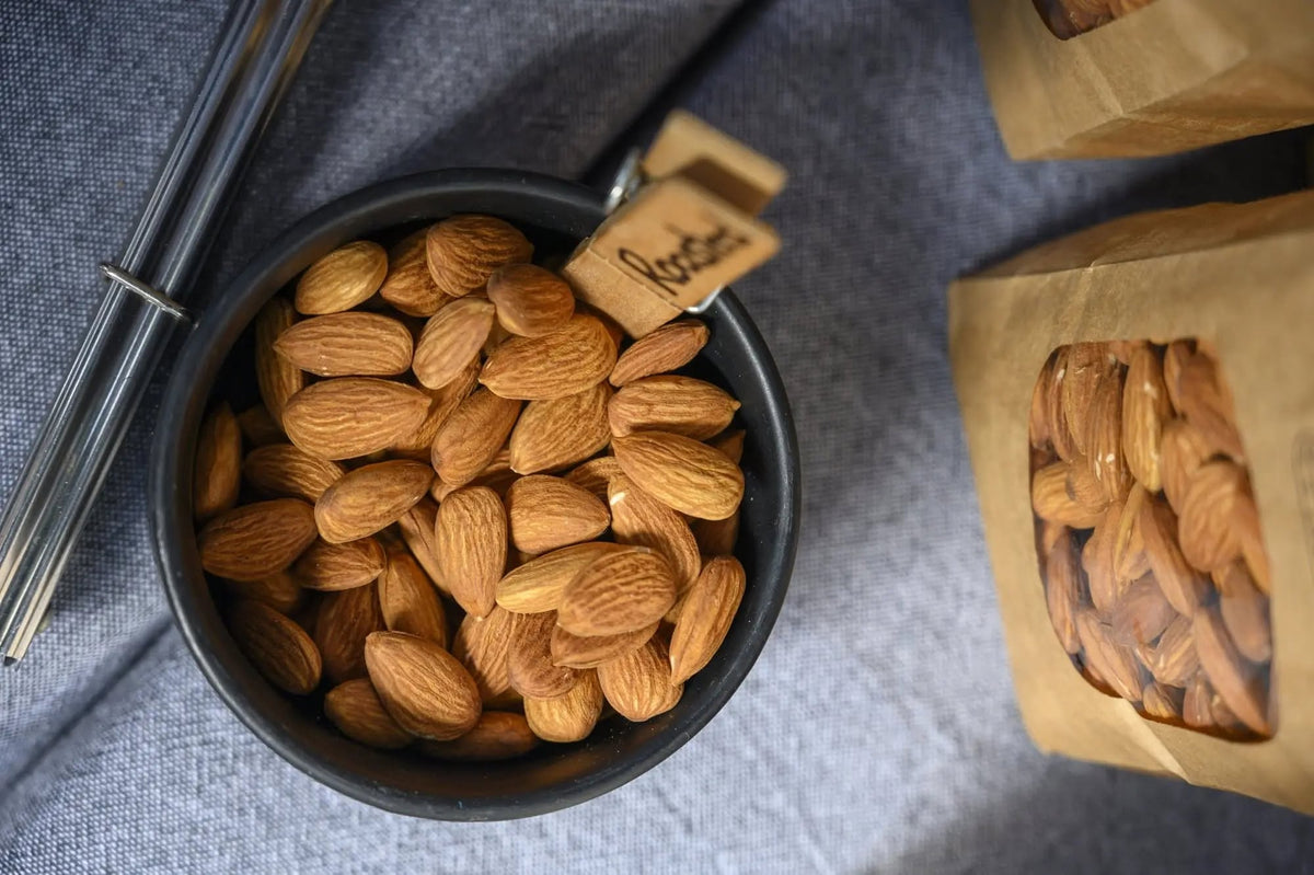 A bowl of Taronga Almonds Roasted Almonds next to packaged almonds