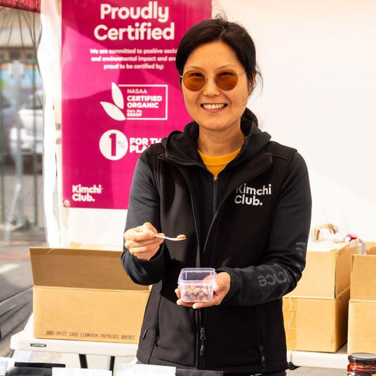 A woman standing at a market offering samples