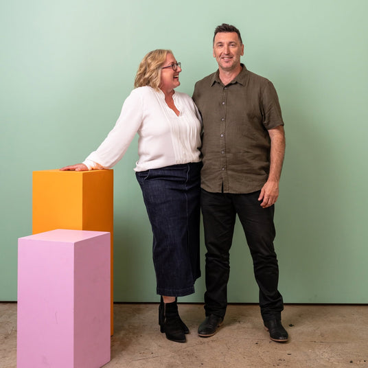 Two people standing in front of a green wall