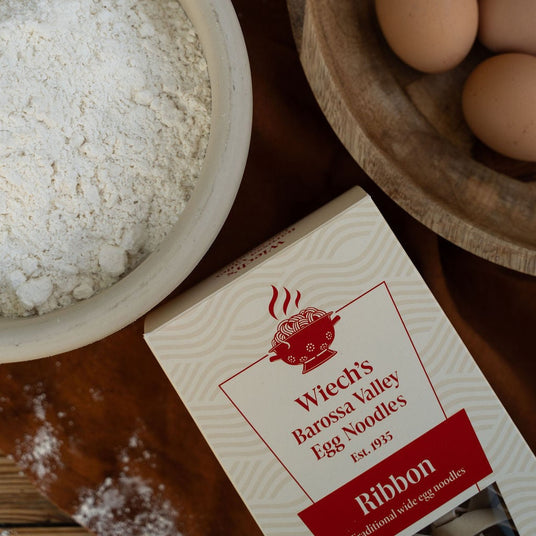 A box of Wiech's Barossa Valley Ribbon Egg Noodles on a table alongside flour and eggs