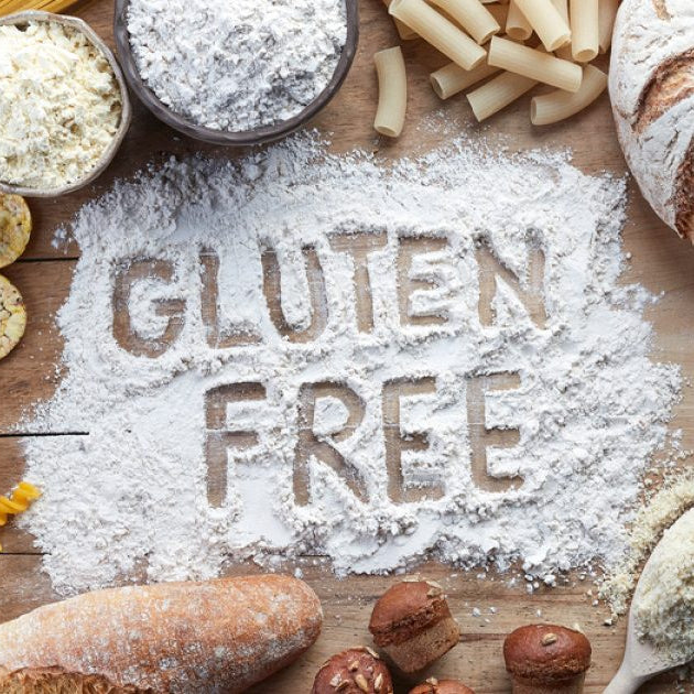Assorted gluten-free breads and pasta on a wooden surface with 'GLUTEN FREE' text.