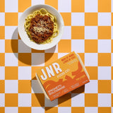 Bowl of spaghetti bolognese with JNR Food Co box on a checkered orange and white background