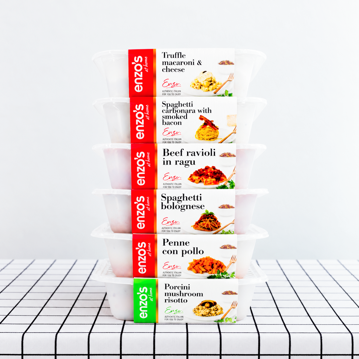 A stack of packaged meals from Enzo's at Home on a table