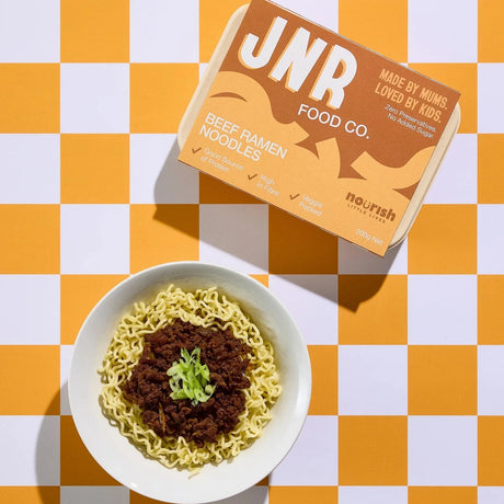 Noodle bowl with a box of JNR Food Co. on a checkered orange and white background