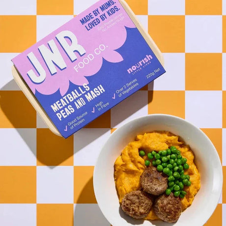 Bowl of mashed sweet potato with meatballs and peas, JNR food box on a checkered background