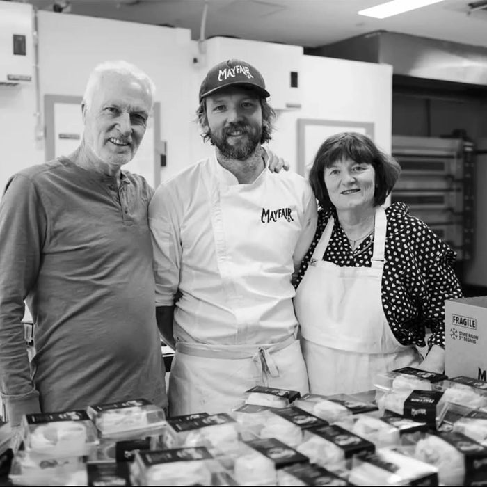 Three people in a kitchen with a display of packaged food items.