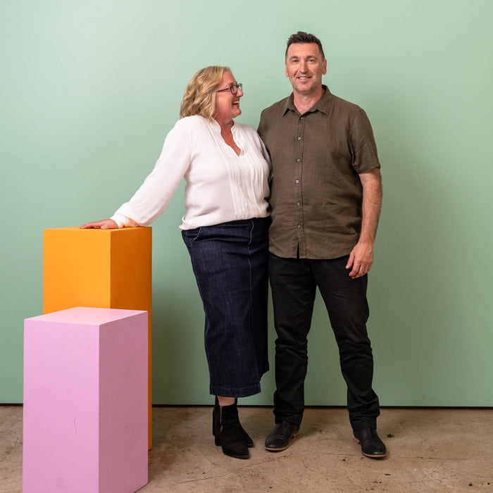 Two people standing in front of a green wall